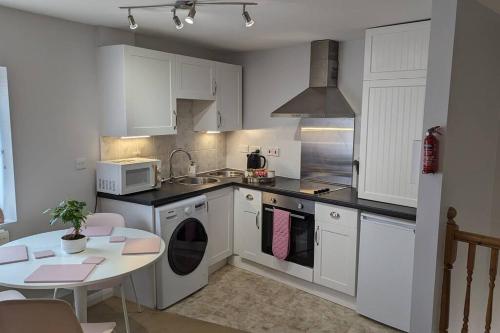 a kitchen with white cabinets and a table and a microwave at Turtle Dove Apartment in Oxford