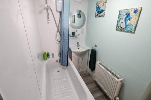 Baño blanco con bañera y lavamanos en Turtle Dove Apartment, en Oxford