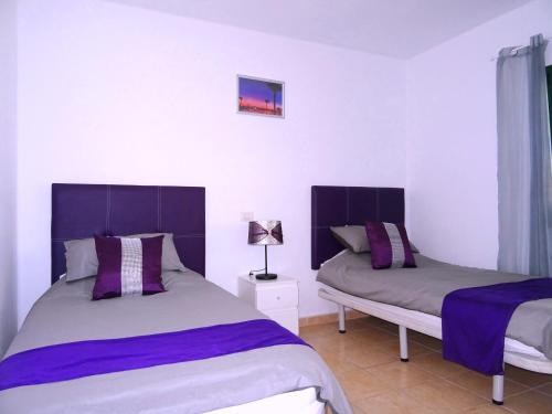 a bedroom with two beds with purple and gray sheets at Puerto Del Carmen - Apartment 5 - Las Palmeras 3 in Puerto del Carmen