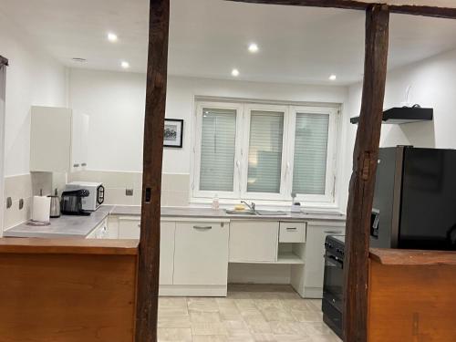 a kitchen with white cabinets and a microwave at La galerie, proche aéroport in Tillé