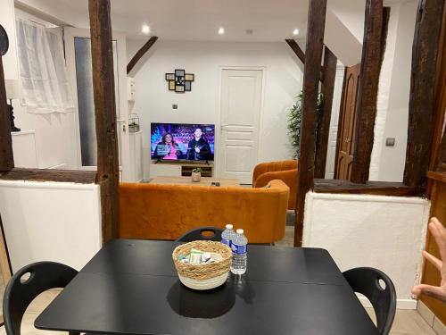 a dining room with a table and a television at La galerie, proche aéroport in Tillé