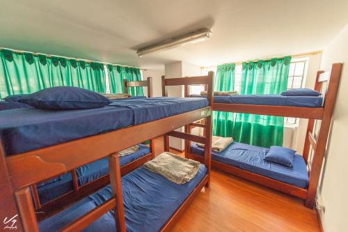 three bunk beds in a room with green curtains at North House Hostel in Bogotá