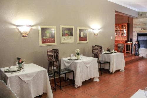 a dining room with two tables with white tablecloths at Siesta Guesthouse & Wedding Venue - Frankfort in Frankfort