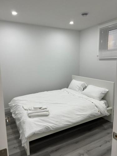 uma cama branca com lençóis brancos e almofadas brancas em Newly built one bedroom 2 bed em Calgary