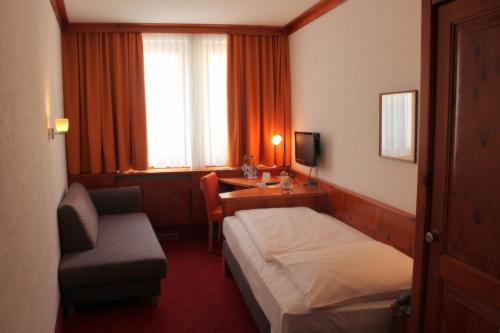 a hotel room with a bed and a chair and a desk at Steichele Hotel & Weinrestaurant in Nuremberg
