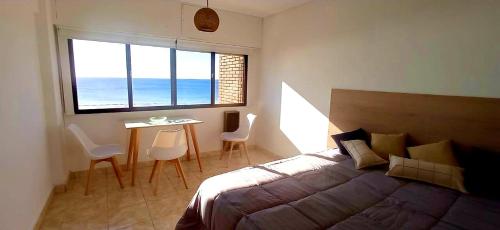 1 dormitorio con 1 cama y 1 mesa con sillas en Amar el mar en Puerto Madryn