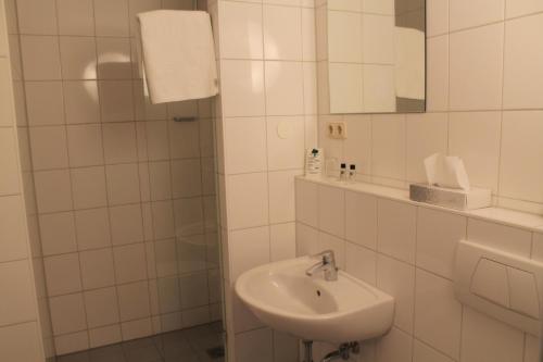 a white bathroom with a sink and a mirror at Steichele Hotel & Weinrestaurant in Nuremberg