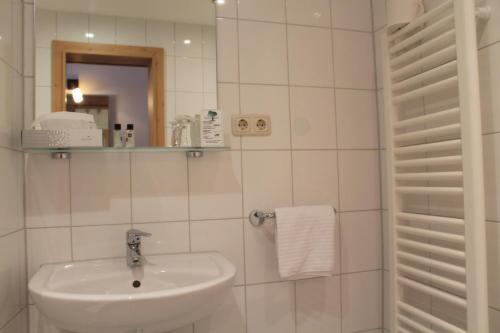 a white bathroom with a sink and a mirror at Steichele Hotel & Weinrestaurant in Nuremberg
