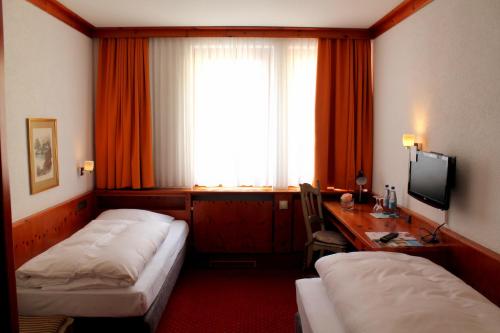 a hotel room with two beds and a desk and a window at Steichele Hotel & Weinrestaurant in Nuremberg