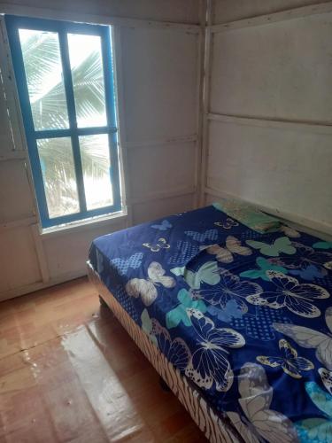 Cama en habitación con manta azul y ventana en La Cabaña, en Montañita