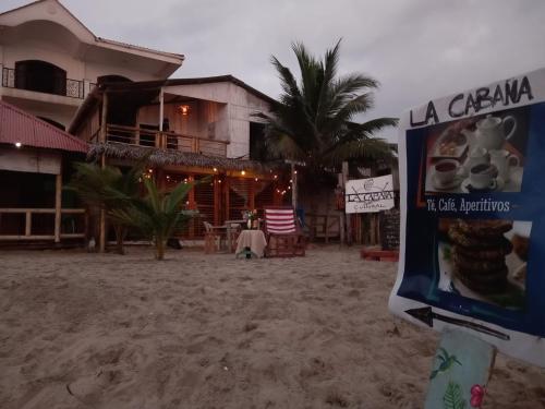 un hotel en la playa con un cartel en el primer plano en La Cabaña, en Montañita