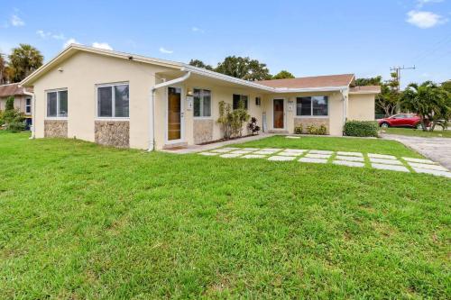 a house with a green lawn in front of it at Cozy AirportHouse 5 min del aeropuerto WiFi parking privado in Dania Beach
