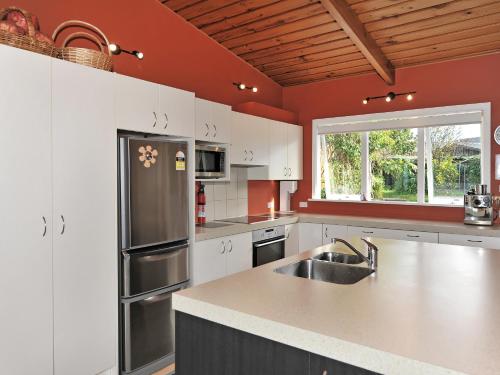 a kitchen with white cabinets and a stainless steel refrigerator at Kereru at Kaiteriteri - Kaiteriteri Holiday Home in Kaiteriteri