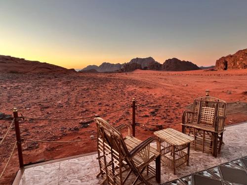 two chairs and a table in the desert at Wadi Rum Sky Tours & Camp in Wadi Rum