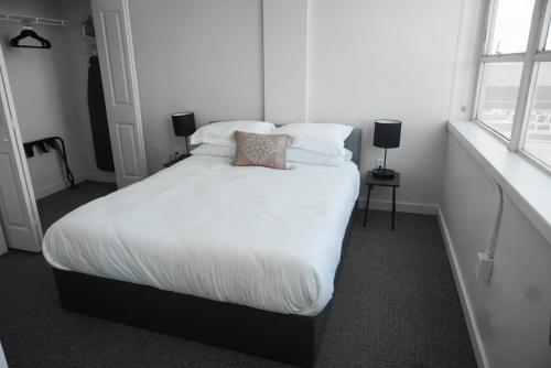 um quarto com uma cama com lençóis brancos e almofadas em Entire High-Rise Apartment - 2BD em Baton Rouge