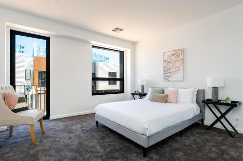 a white bedroom with a bed and a chair at Urban Rest Port Adelaide Apartments in Port Adelaide