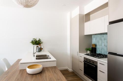 a white kitchen with a sink and a stove at Urban Rest Port Adelaide Apartments in Port Adelaide