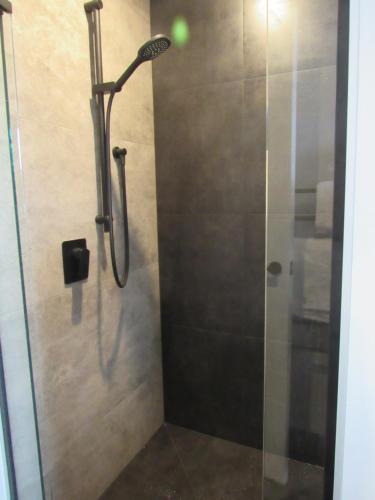 a shower in a bathroom with a glass door at Llun y Mynydd B&B Nelson in Nelson