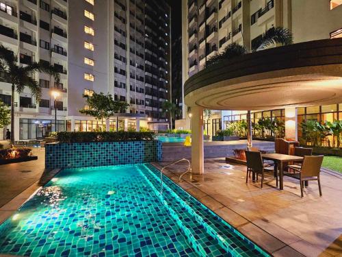 a pool with a table and chairs in a building at SM Spring Residences Tower 2 Condominium Bicutan Parañaque Cozy Condo in Manila