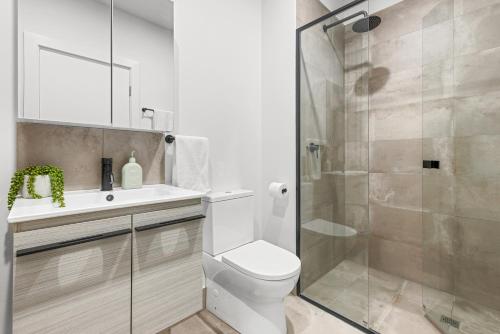 uma casa de banho com um WC e uma cabina de duche em vidro. em Urban Rest Port Adelaide Apartments em Port Adelaide