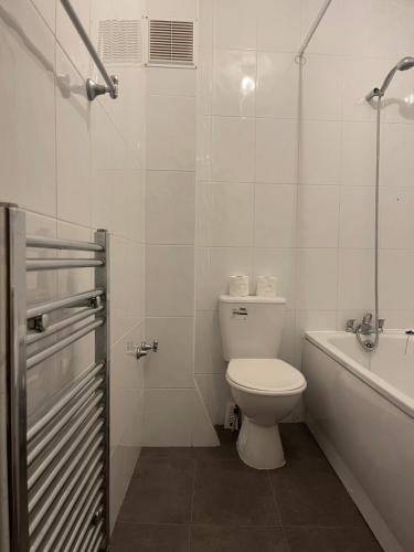 a white bathroom with a toilet and a bath tub at Stratford Guest House By Cosystays in London