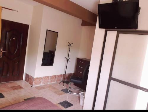 a living room with a tv and a mirror at HOTEL ANAHÍ in Chulumani