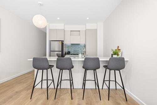 a kitchen with a table and four stools at Urban Rest Port Adelaide Apartments in Port Adelaide