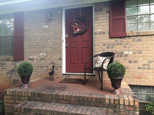 a brick house with a red door and a bench at Quiet Kennesaw 3BR home - close to KSU, Lakepoint in Kennesaw