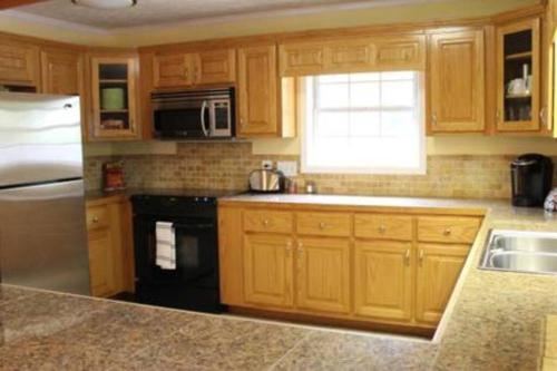 a kitchen with wooden cabinets and a sink and a refrigerator at Quiet Kennesaw 3BR home - close to KSU, Lakepoint in Kennesaw