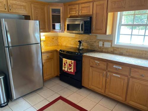 a kitchen with wooden cabinets and a stainless steel refrigerator at Quiet Kennesaw 3BR home - close to KSU, Lakepoint in Kennesaw