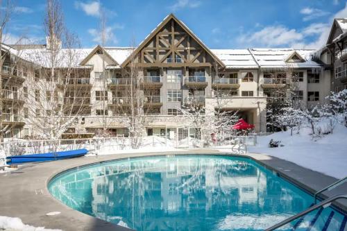 a large apartment building with a swimming pool in the snow at 1BR in The Aspens, King Bed, True Ski In, Ski Out, Hot Tubs and Pool, Ski Valet, Private Balcony in Whistler