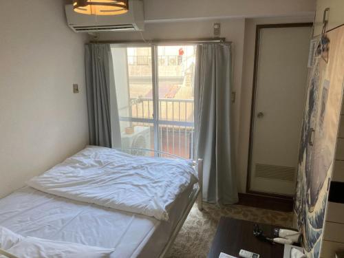 um pequeno quarto com uma cama e uma varanda em Nishimoto Building - Vacation STAY 16010v em Hiroshima