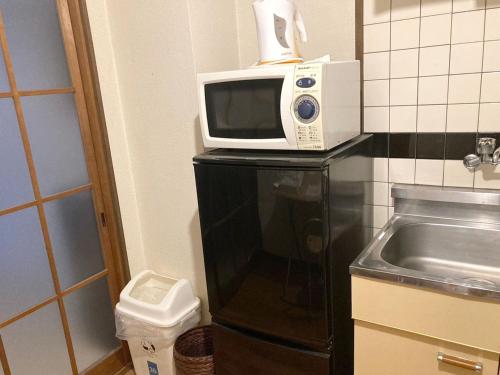 um micro-ondas sentado em cima de um frigorífico preto em Nishimoto Building - Vacation STAY 16015v em Hiroshima