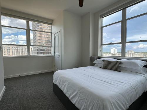 a white bedroom with large windows and a bed at Stylish Downtown High-Rise - 2BD in Baton Rouge