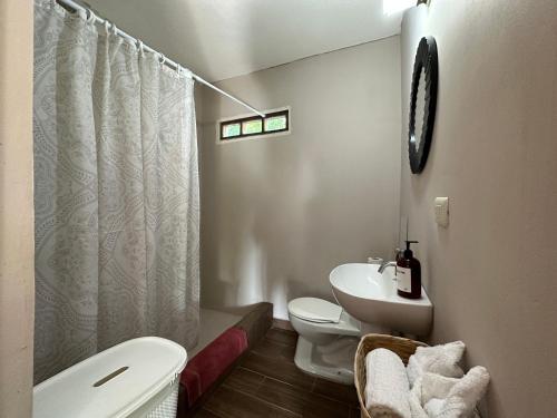 a white bathroom with a toilet and a sink at Hotel Atelie del Mar in Monterrico