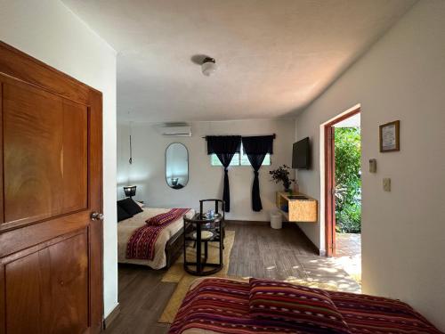 a bedroom with a bed and a table and a door at Hotel Atelie del Mar in Monterrico