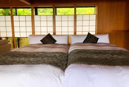 two beds sitting next to each other in a bedroom at Hyakunagaran in Nanjo