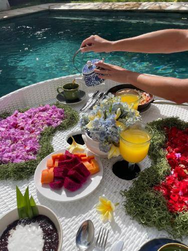 una mesa con comida y bebidas junto a una piscina en Villa Gekyu, en Jimbaran