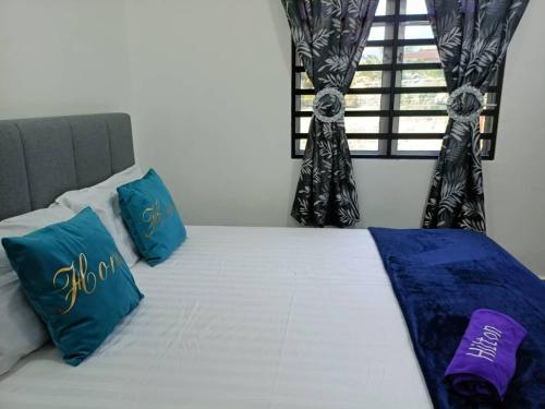 - un lit avec des oreillers bleus et blancs et une fenêtre dans l'établissement Adiniz@HotSpring Sg Klah, à Sungkai