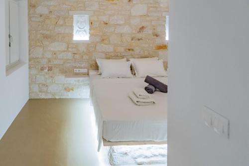 a bedroom with a white bed and a stone wall at Aegean Feelings in Piso Livadi