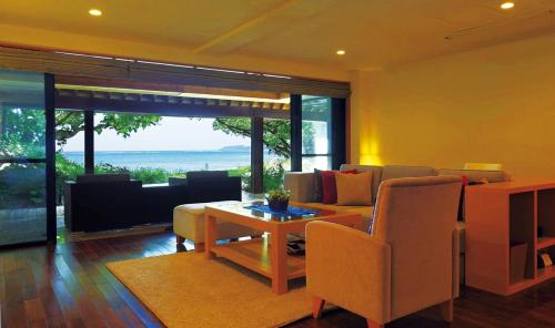 a living room with a couch and a table and chairs at Hyakunagaran in Nanjo