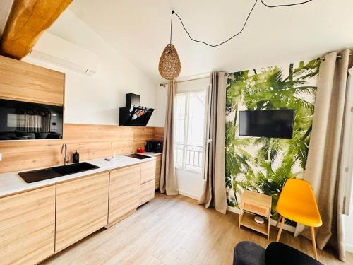 une cuisine avec des placards en bois et une chaise jaune dans l'établissement Les Appartements de Nana 12 - Studio hypercentre, Rue Meynadier, Palais & Plage, clim, wifi, à Cannes