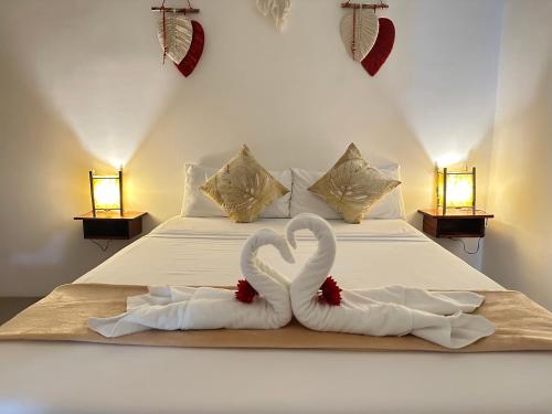two white swans towels on a bed with two lights at Rvilla El Nido in El Nido