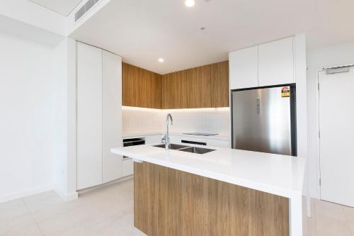 a kitchen with white cabinets and a stainless steel refrigerator at Solaris 410 in Forster