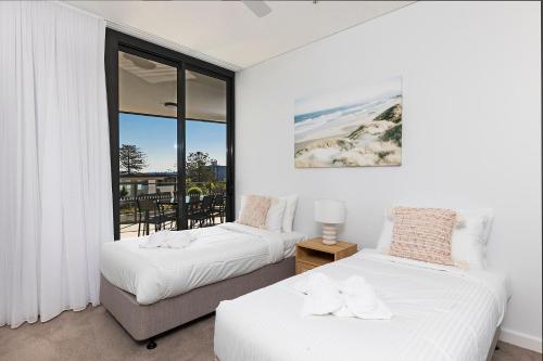 two beds in a room with a balcony at Solaris 410 in Forster