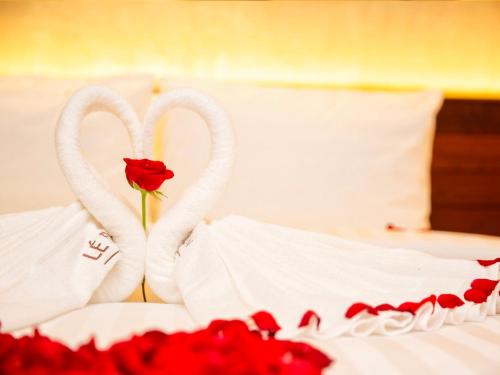 two swans shaped like hearts on a bed with a rose at Le Botum Hotel in Phnom Penh