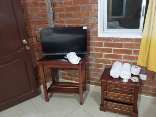 una mesa pequeña con TV y una mesa con toallas en Hostería Cacique Wasi, en Puyo