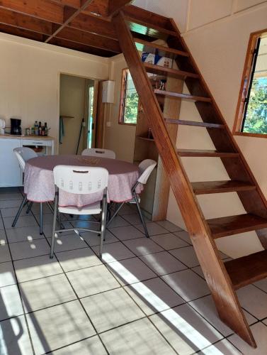una habitación con una mesa y una escalera en una casa en Le chalet Scarlet, en Teahupoo