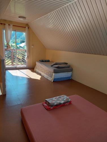 een zolderkamer met 2 bedden en een tapijt bij Le chalet Scarlet in Teahupoo