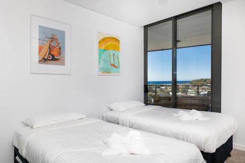 two beds in a white room with a window at Solaris 606 in Forster